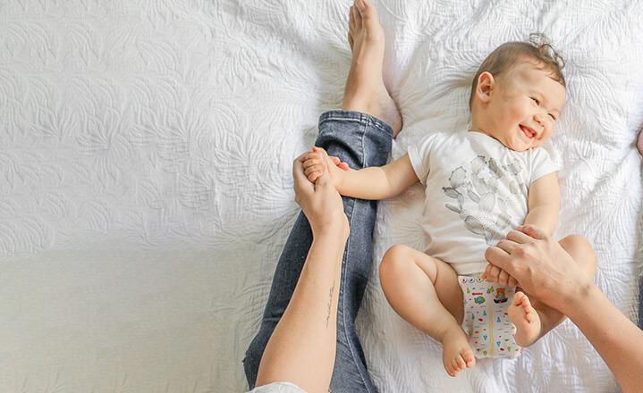 Mother playing with baby on bed
